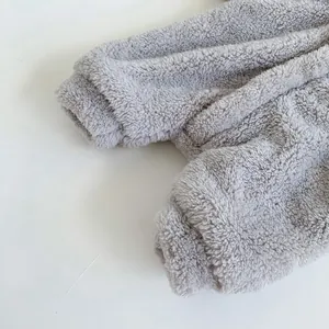 Detail of soft grey sherpa fleece baby jumpsuit featuring elastic cuffs and warm texture