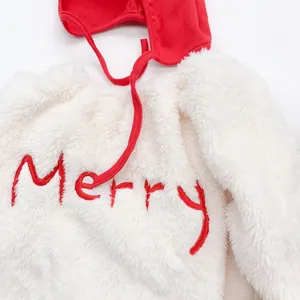 Close-up of white plush baby bodysuit with red Merry embroidery and matching Christmas hat