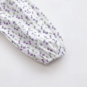 Close-up of elastic cuffs and purple floral pattern on baby long sleeve bodysuit