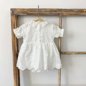 Detail of baby girl floral romper with lace edges and delicate embroidery