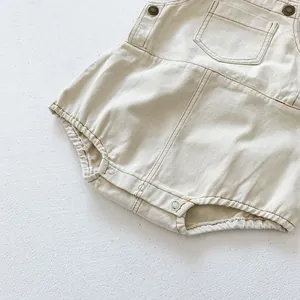 Detail of baby denim romper with contrast stitching, metal buttons and soft cotton fabric