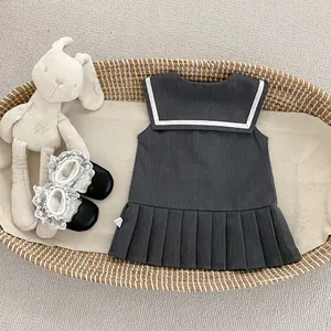 Vestido gris estilo marinero para bebé con ribete blanco en una cesta tejida