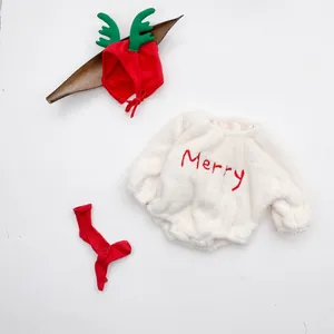 Detail of baby Christmas set featuring white plush romper with Merry embroidery and festive deer hat