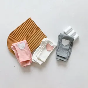 Vue détaillée de trois leggings en coton pour bébé avec broderie en forme de cœur