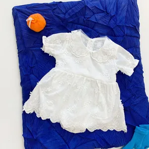 Detail of white infant romper dress with floral embroidery and Peter Pan collar