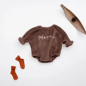 Detail of baby brown fleece romper with Merry embroidery and orange striped socks