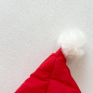 Detailed close-up of soft red winter baby hood with a large white fluffy pompom decoration