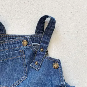 Detail of baby denim romper featuring vintage metal buttons and contrast stitching