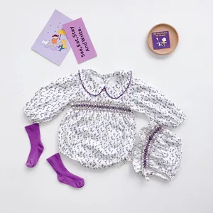 Detail of purple floral baby romper set with smocked chest, matching hat and ribbed socks