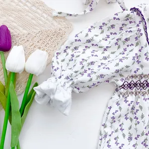 Detail of floral baby bodysuit with purple smocked embroidery and ruffled elastic cuffs