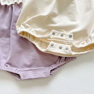 Close-up of cotton baby rompers with lace trim and convenient bottom snap buttons