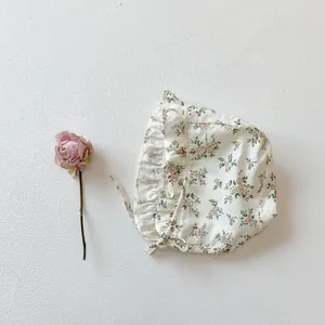 Close-up of floral baby sun hat with ruffled edges and chin strap in vintage style