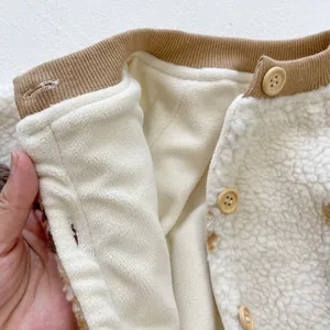 Detail of baby plush romper showing soft fleece lining and natural wooden button closure