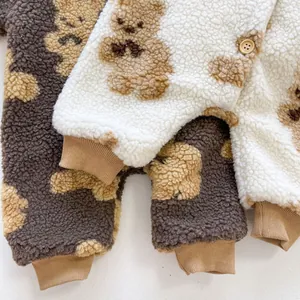 Detail view of baby bear print jumpsuits featuring sherpa fleece fabric and wooden buttons