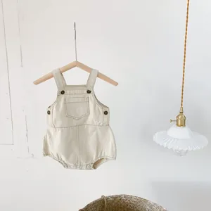 Detail of baby cream cotton romper featuring chest pocket and side metal buttons