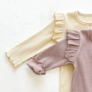 Detail of baby cotton rib rompers with ruffled shoulders and lettuce edge in soft pastels