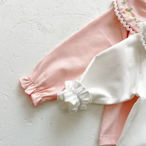 Close-up of cotton baby tops featuring floral embroidery and delicate ruffle cuffs