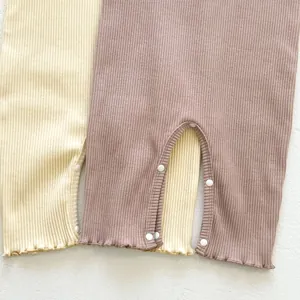 Detailed view of ribbed knit cotton fabric with snap buttons and ruffled hem on baby rompers