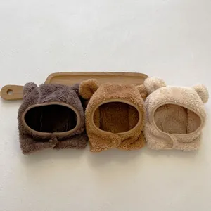 Three plush baby hats with bear ears in brown, caramel, and cream colors with buttons