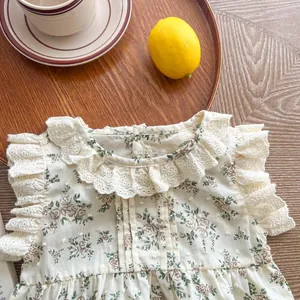 Floral baby romper with lace collar and ruffle sleeves on a rustic wooden tray