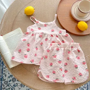Completo estivo vichy per neonata con stampe di fragole su un tavolo in legno
