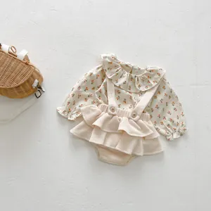 Ensemble bébé avec imprimé floral, col à volants et pantalon à bretelles sur fond blanc