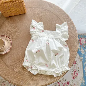 Detail of white cotton baby bodysuit with pink floral embroidery and ruffled sleeves