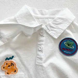 Détail de chemise bébé en coton blanc avec broderie dessin animé et motif d'ours