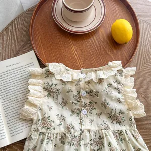 Detailed view of floral cotton baby romper with lace collar and wooden props background