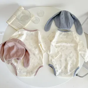 Flat lay of cotton baby bodysuits with bunny prints and matching long-ear hats