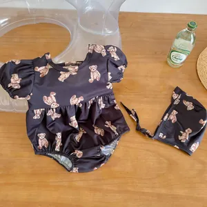 Detail of baby girl swimsuit with bear print, puff sleeves and matching sun hat