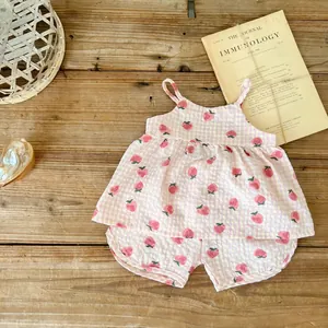 Dettaglio completo estivo neonata a quadretti rosa con fragole su sfondo di legno naturale