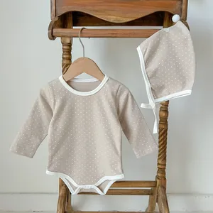 Infant long sleeve polka dot romper with matching baby hat on a wooden hanger