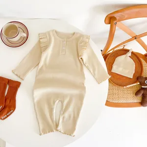 Detailed flat lay of beige ribbed baby romper set with wood buttons and frill sleeves