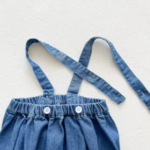 Détail du barboteuse en jean bébé avec taille élastique et boutons blancs réglables