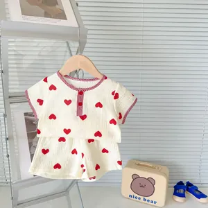 Detail of baby cotton gauze set featuring red heart prints and functional buttons