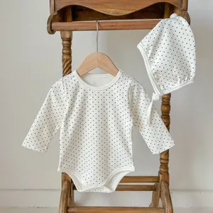 Detailed view of polka dot baby romper set with matching hat on a wooden hanger