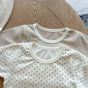 Close-up of baby bodysuits with polka dot patterns and fine knit crew neck details