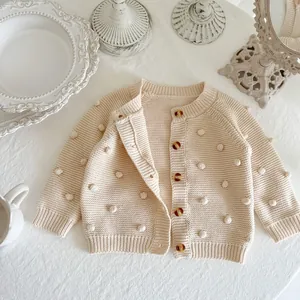 Cream knit cardigan for baby girls with 3D pom-poms and amber buttons