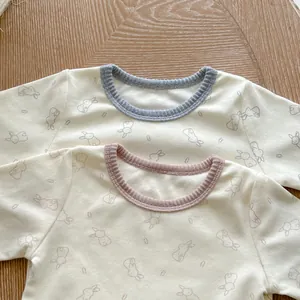 Detail of soft cotton baby bodysuit featuring cute bunny print and ribbed crew neckline