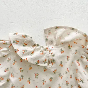 Détail d'une barboteuse fleurie pour bébé avec col à volants et fermeture boutonnée
