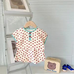 Close-up of baby floral cotton set with green plaid trim and red buttons for summer