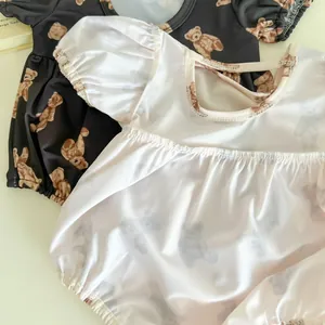Detail of baby bodysuits featuring bubble sleeves and brown bear prints on cotton fabric