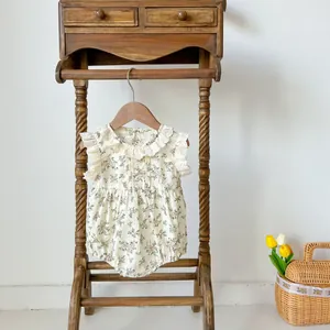 Detail of baby floral romper with lace collar and flutter sleeves on a wooden hanger