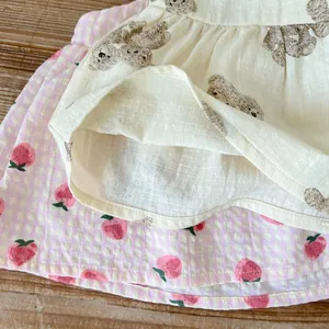 Dettaglio del set neonato con stampe di orsetti, motivi di fragole e trama in cotone lino