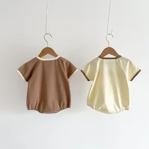 Detailed view of two short-sleeve cotton baby rompers with contrast piping details