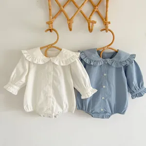 Détail d'un barboteuse pour bébé avec col à volants et cintres en bois sur crochet en rotin