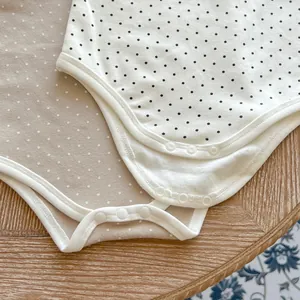 Detail of snap button closure and soft cotton fabric on polka dot baby bodysuits