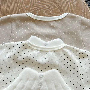 Detail of infant polka dot romper with detachable plush angel wings and button clasp