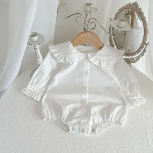 Barboteuse blanche bébé à manches longues avec col à volants sur un cintre en bois